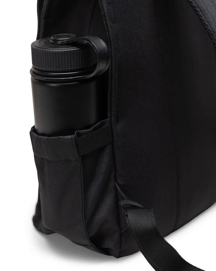 A closeup of a water bottle in a black backpack on a white background