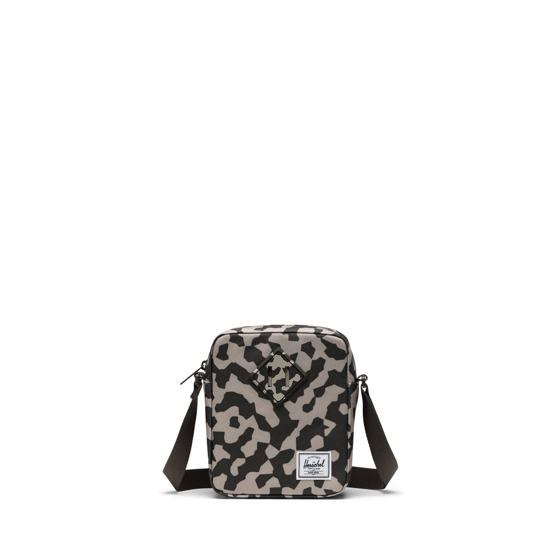 A camo Herschel Heritage crossbody bag with an adjustable strap and a signature diamond detail on the front.