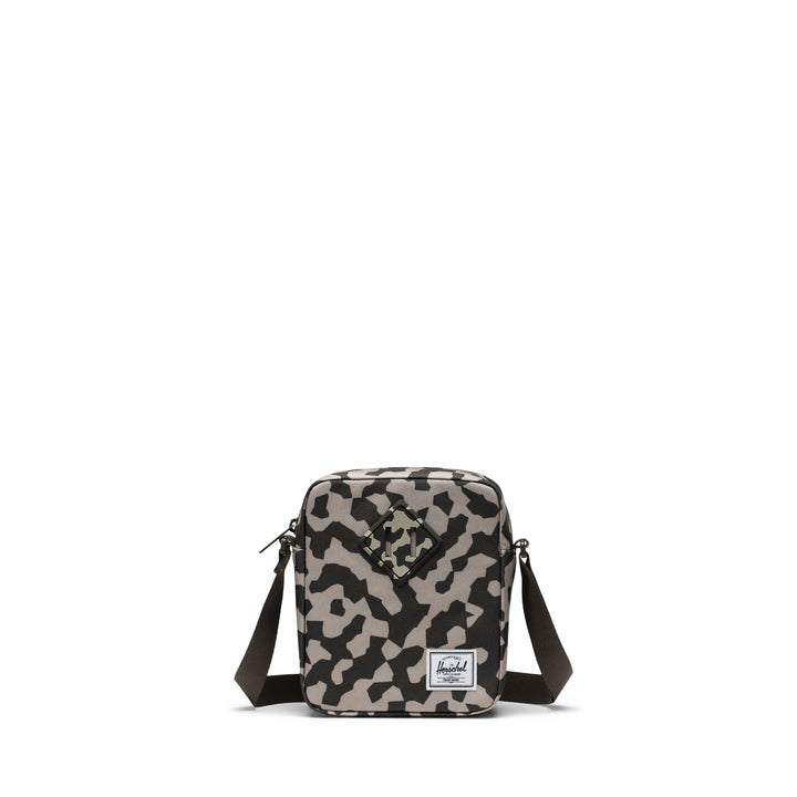 A camo Herschel Heritage crossbody bag with an adjustable strap and a signature diamond detail on the front.