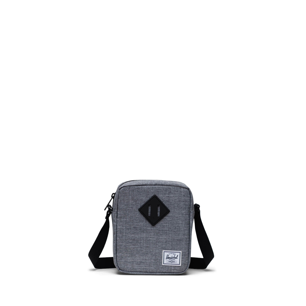 A grey Herschel Heritage crossbody bag with an adjustable strap and a signature diamond detail on the front.