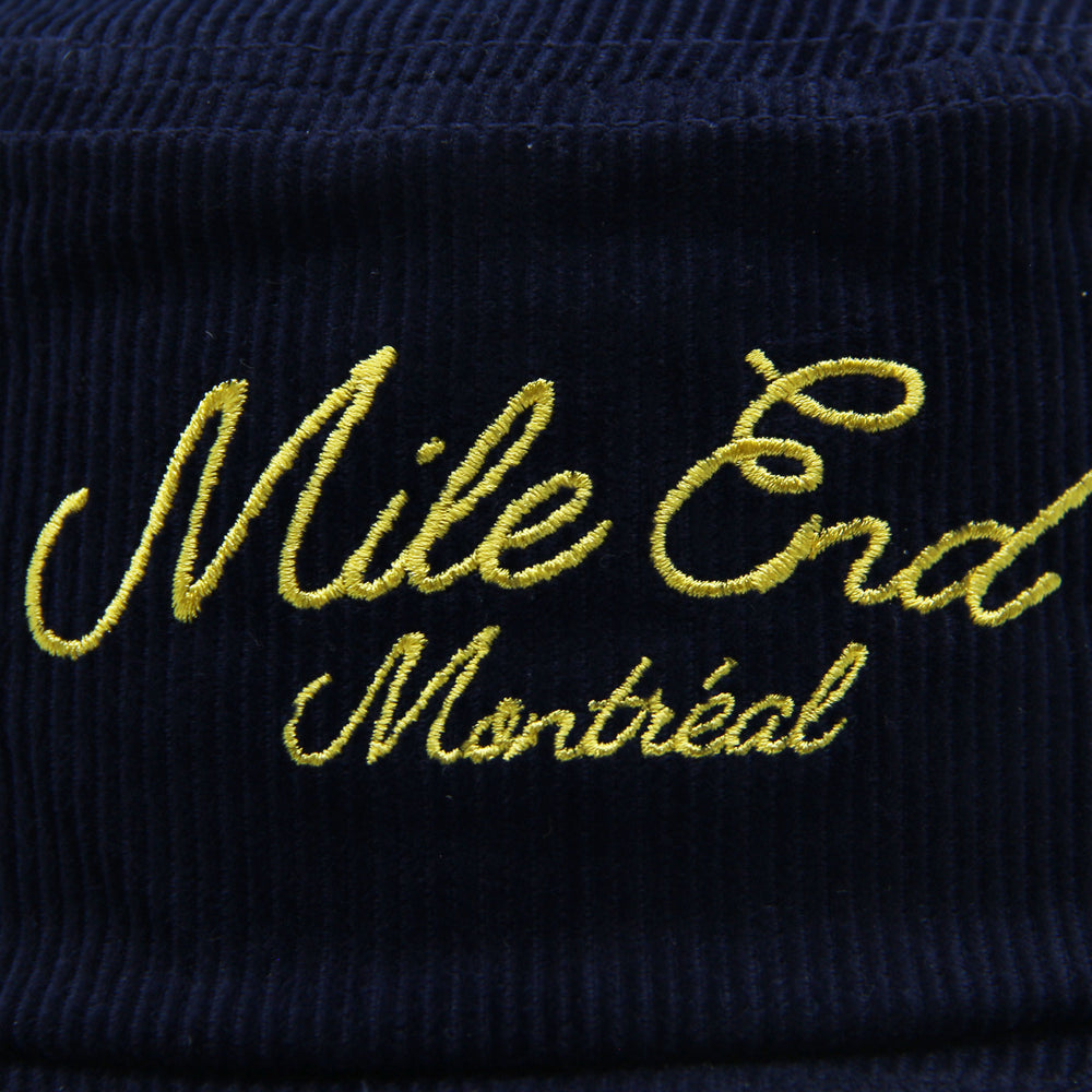Navy blue corduroy hat with yellow embroidered text 'Mile End Montreal'