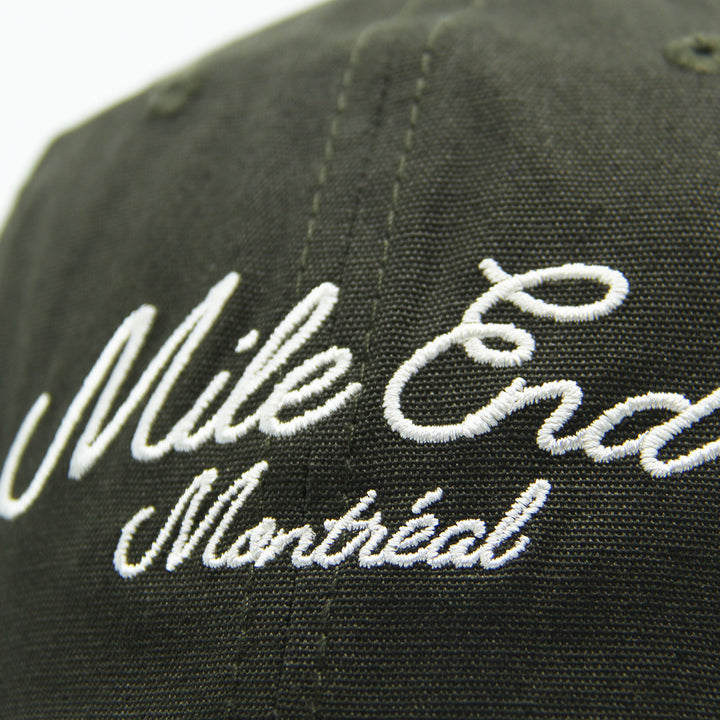 Green cap with 'Mile End Montreal' embroidered in white on a white background