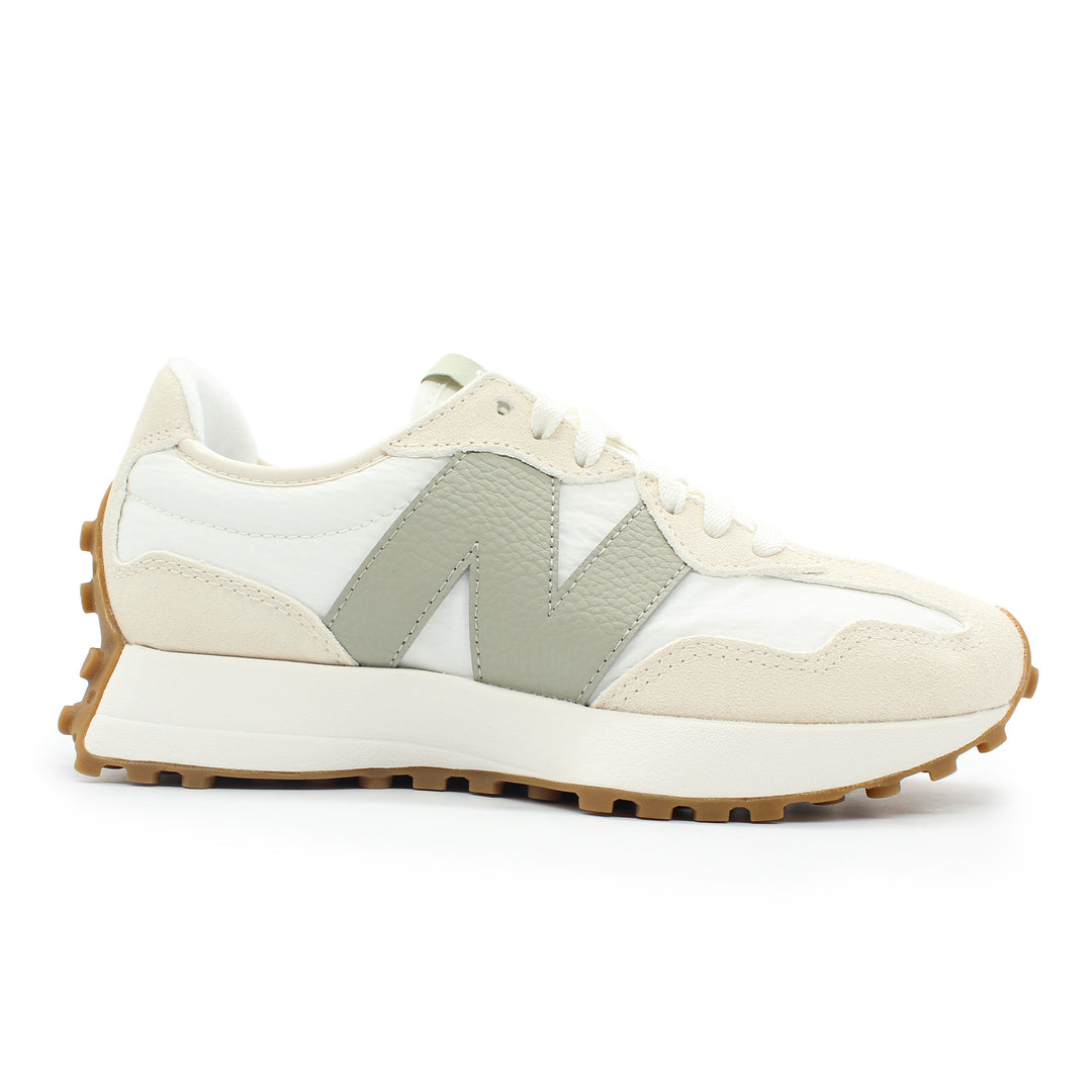 A white New Balance shoe shown from the side view. The sole is gum and wraps around the heel of the shoe. There is contrasting colors of white and cream throughout the shoe.