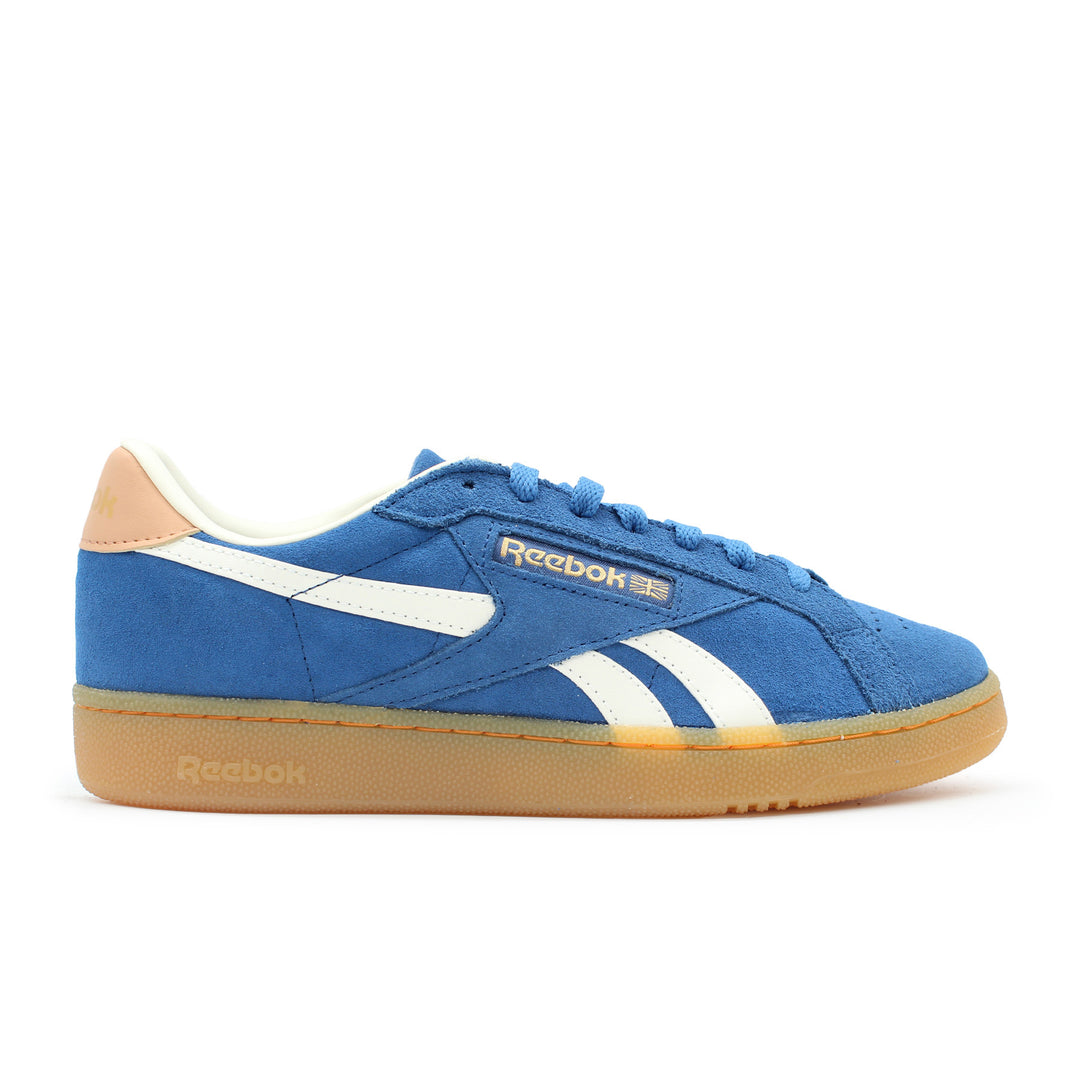 The side view of a blue Reebok shoe with a gum sole. The shoe has white and beige accents.
