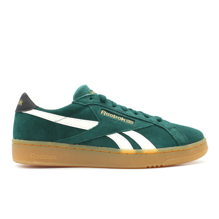 The side view of a dark green suede Reebok shoe on a white background. The shoe has a gum slightly translucent sole and midsole. It has white and gold accents.