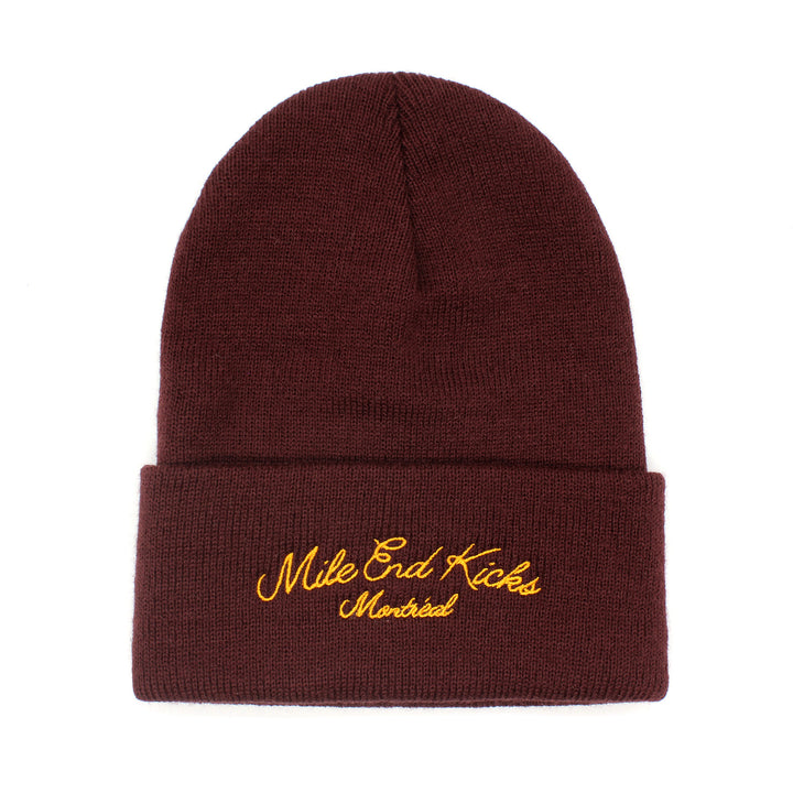 Red beanie with 'Mile End Kicks Montreal' embroidery on a white background