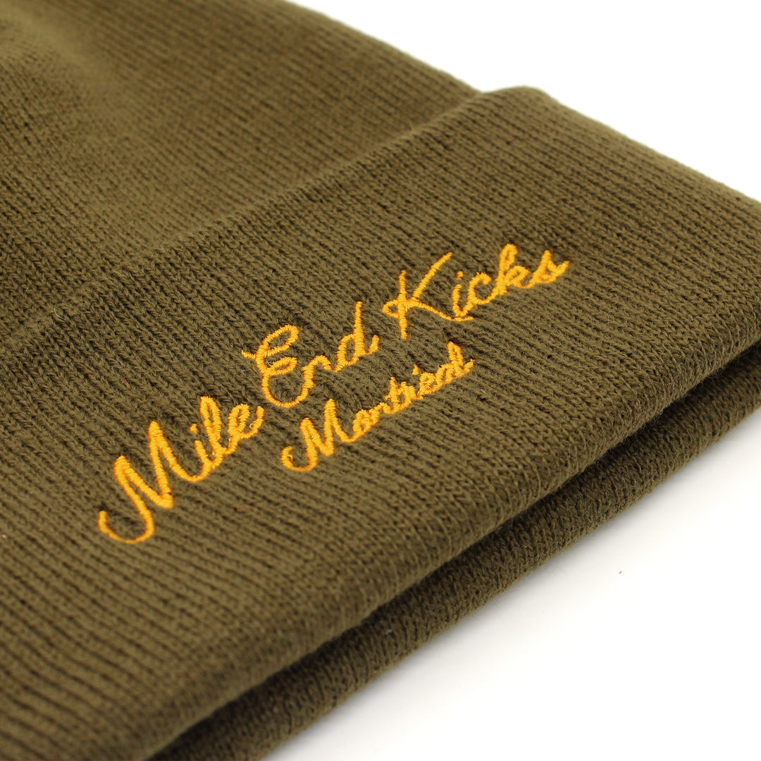 Green knit beanie with 'Mile End Kicks Montreal' embroidery on a white background