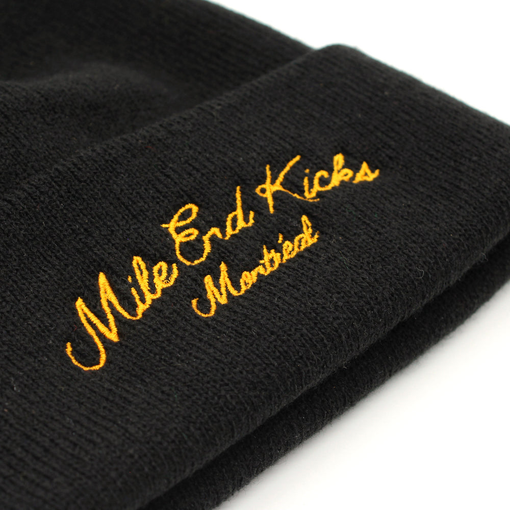 Black beanie with yellow embroidered text on a white background