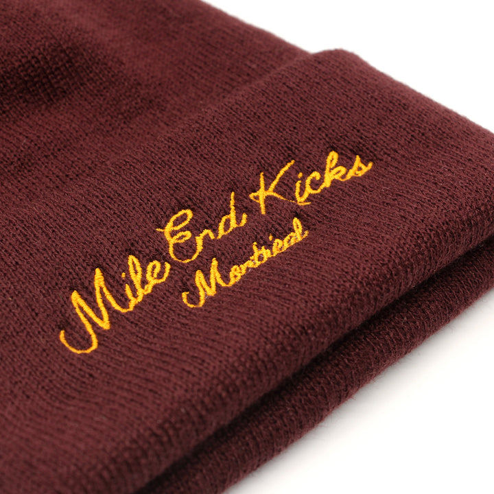 Red beanie with 'Mile End Kicks Montreal' embroidery on a white background