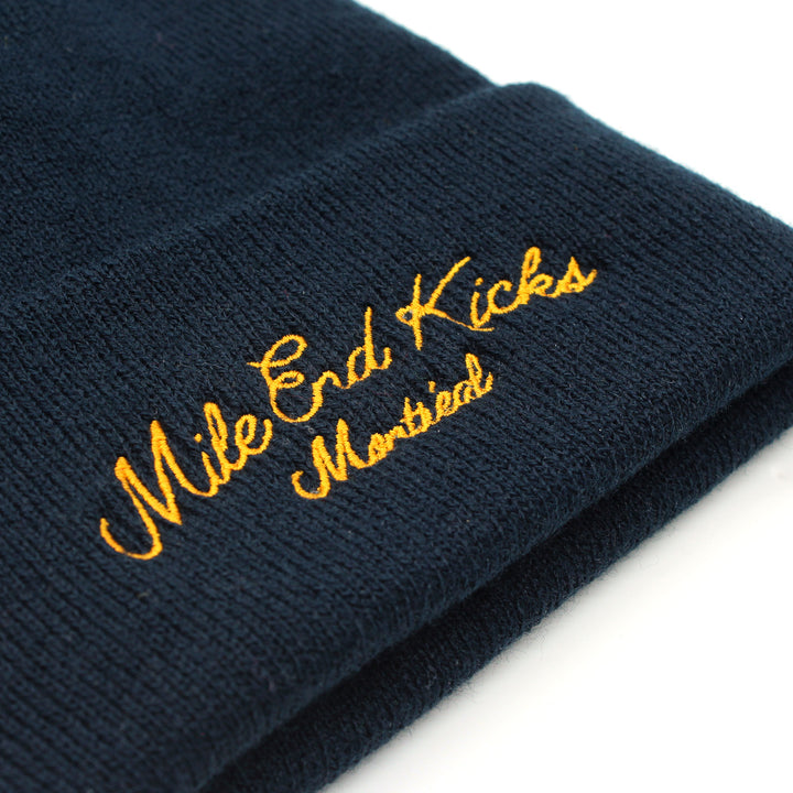 Navy blue beanie with 'Mile End Kicks Montreal' embroidered in yellow on a white background
