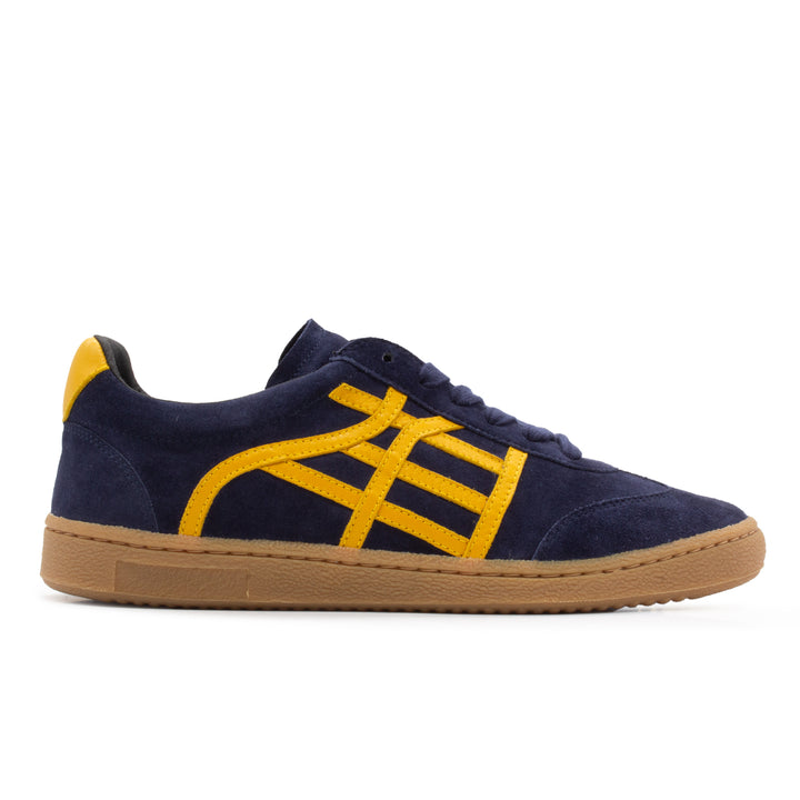 A dark navy and yellow shoe with a gum sole. The shoe is made out of navy suede with yellow accents.