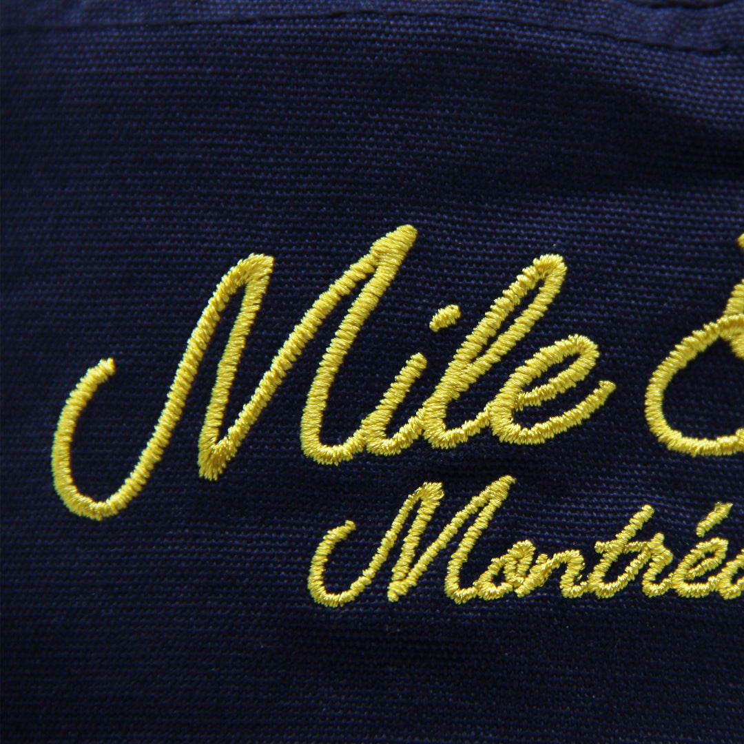 Navy blue hat with yellow embroidered text 'Mile End Montréal'.