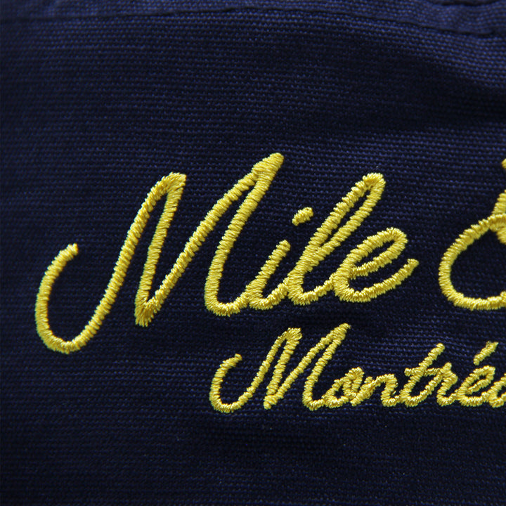 Navy blue hat with yellow embroidered text 'Mile End Montréal'.