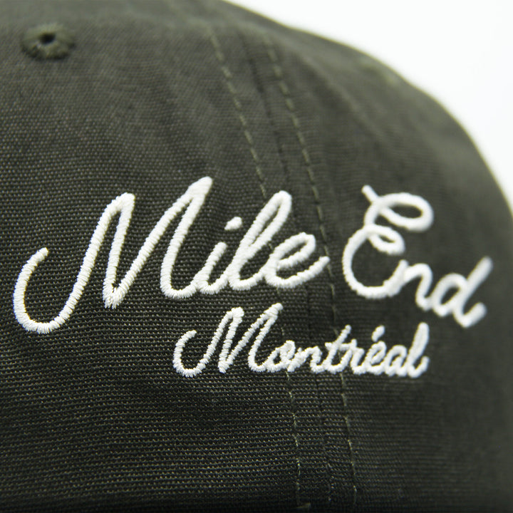 Green cap with 'Mile End Montreal' embroidered in white on a white background