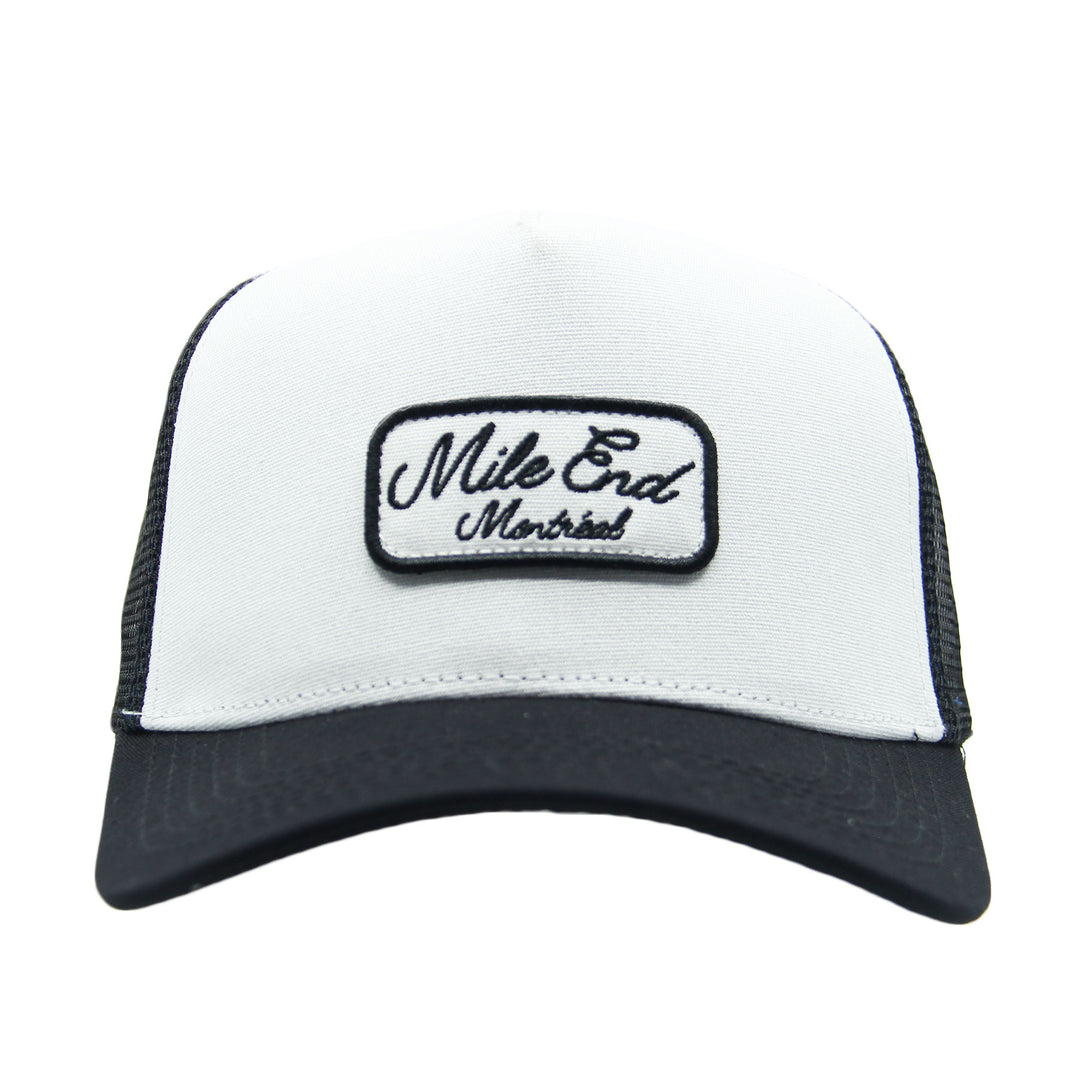 White and black cap with 'Mile End Montreal' patch on a white background