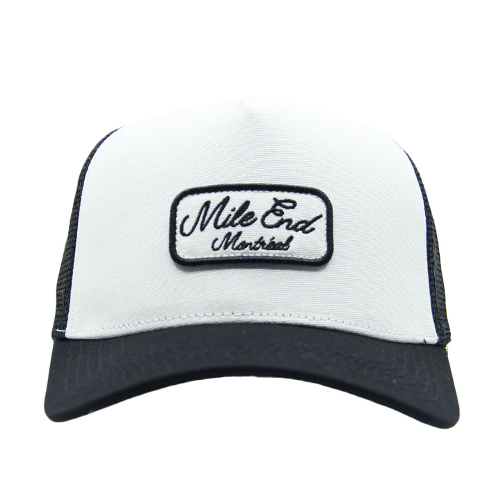 White and black cap with 'Mile End Montreal' patch on a white background