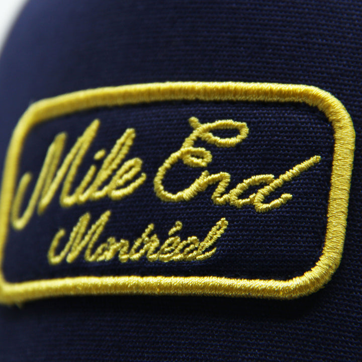 Navy blue cap with yellow embroidered text 'Mile End Montreal'
