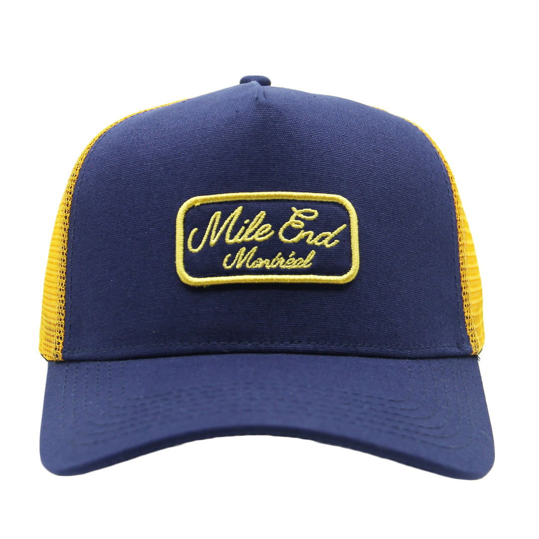Blue and yellow cap with 'Mile End Montreal' logo on a white background