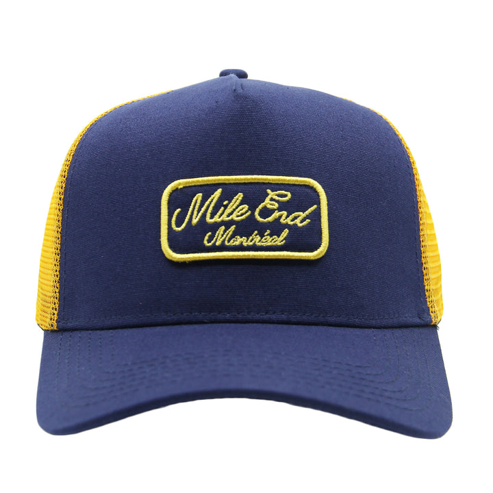Blue and yellow cap with 'Mile End Montreal' logo on a white background