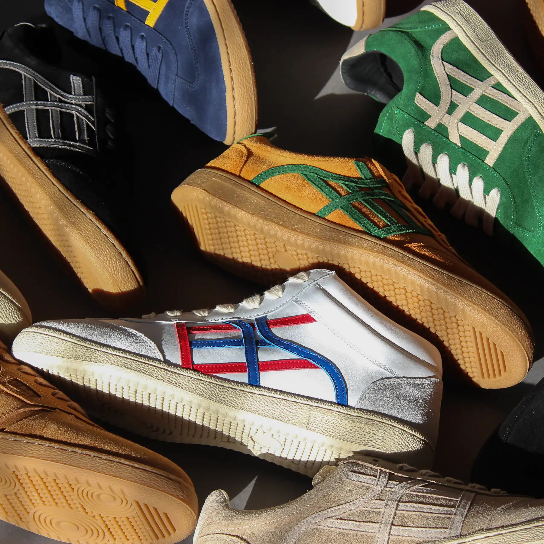 Several shoes of different colors next to each other. The image is taken from a top view. Light and shadows add contrast to the image.