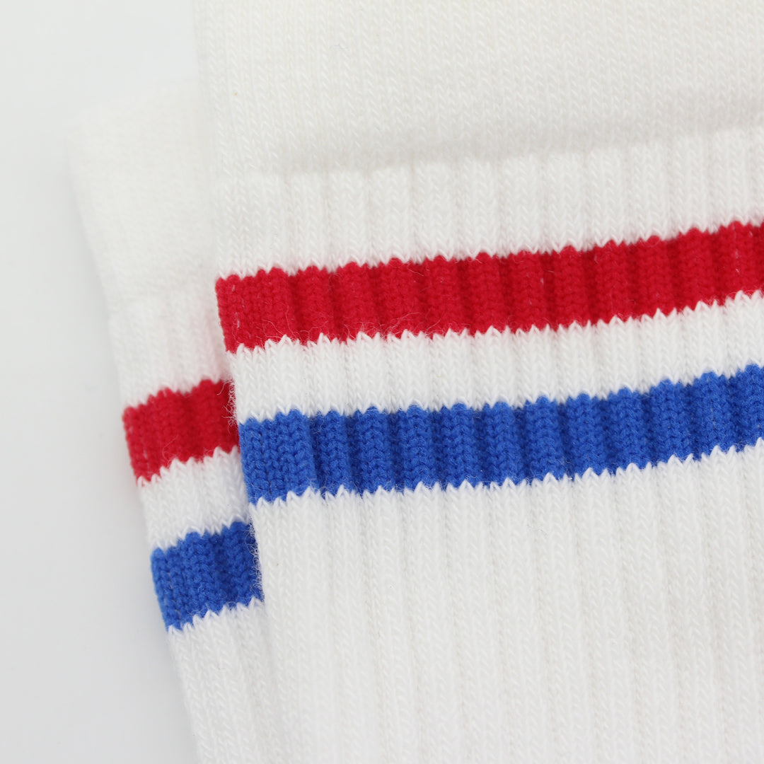 Close-up of white socks with red and blue stripes on a light gray background