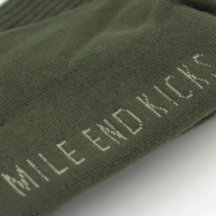 Green sock with 'Mile End Kicks' branding on a white background