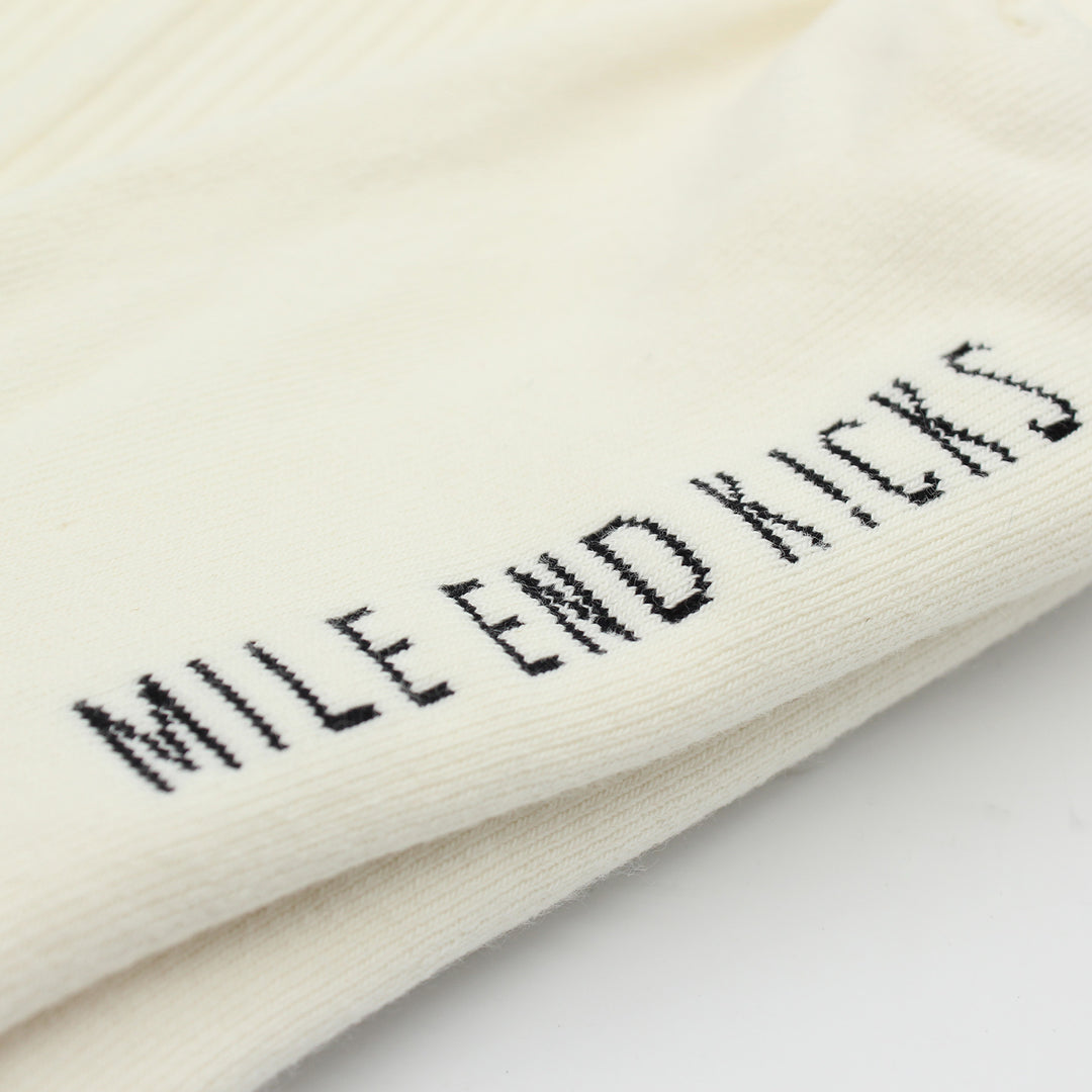 White socks with 'Mile End Kicks' embroidery on a light background
