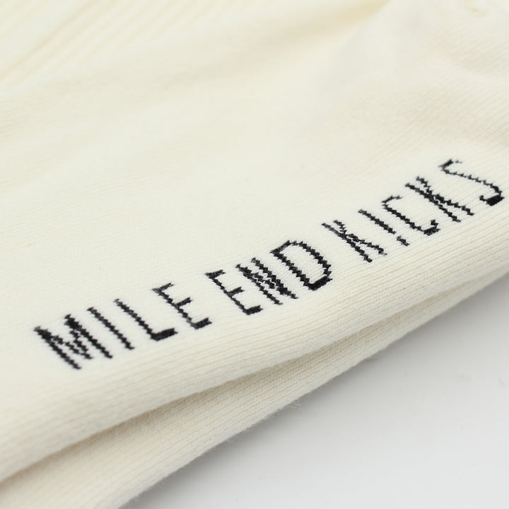 White socks with 'Mile End Kicks' embroidery on a light background