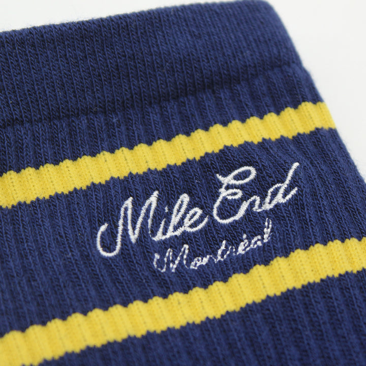 Navy blue sock with yellow stripes and 'Mile End Montreal' text
