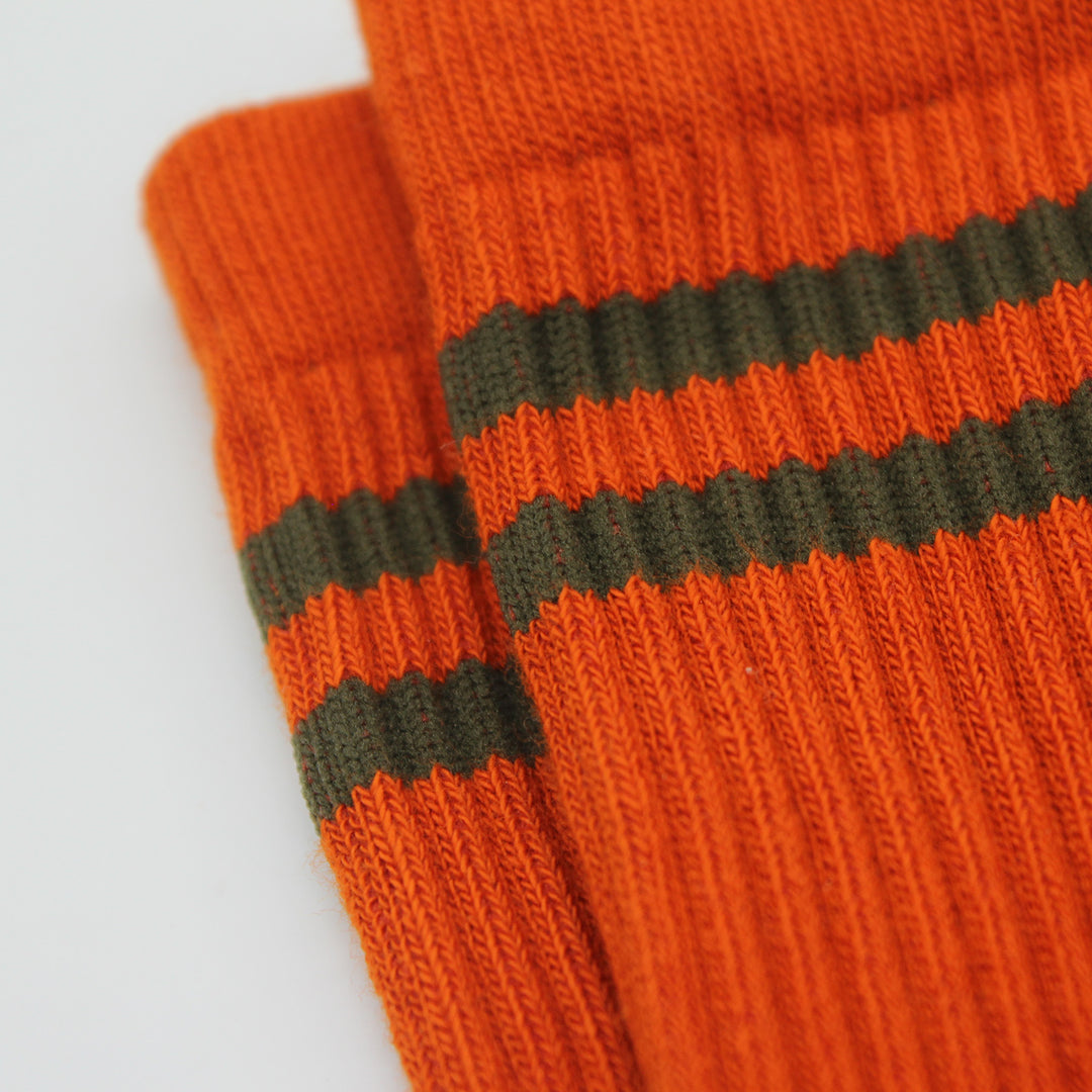 Close-up of orange socks with green stripes on a light gray background