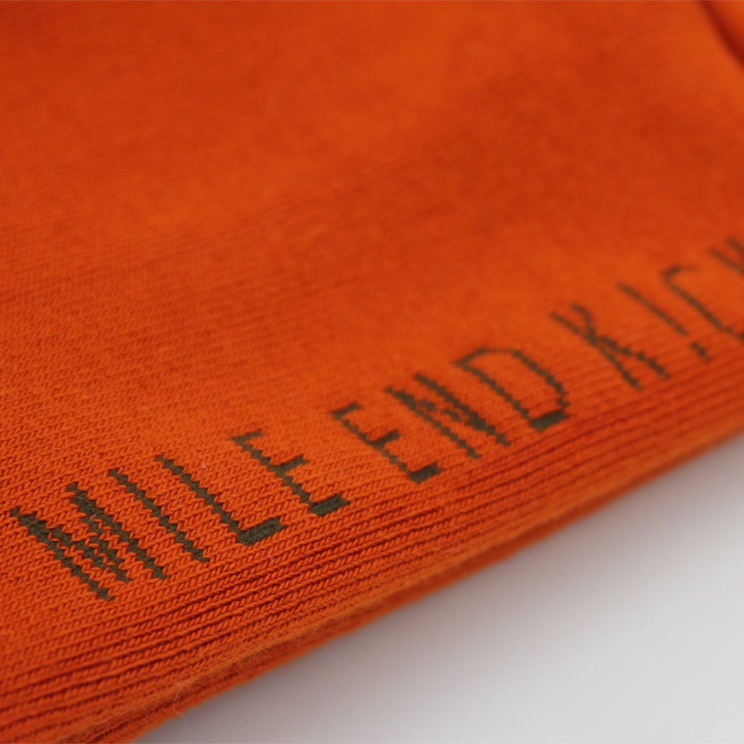 Close-up of orange socks with 'MILE END KICKS' embroidered on it.
