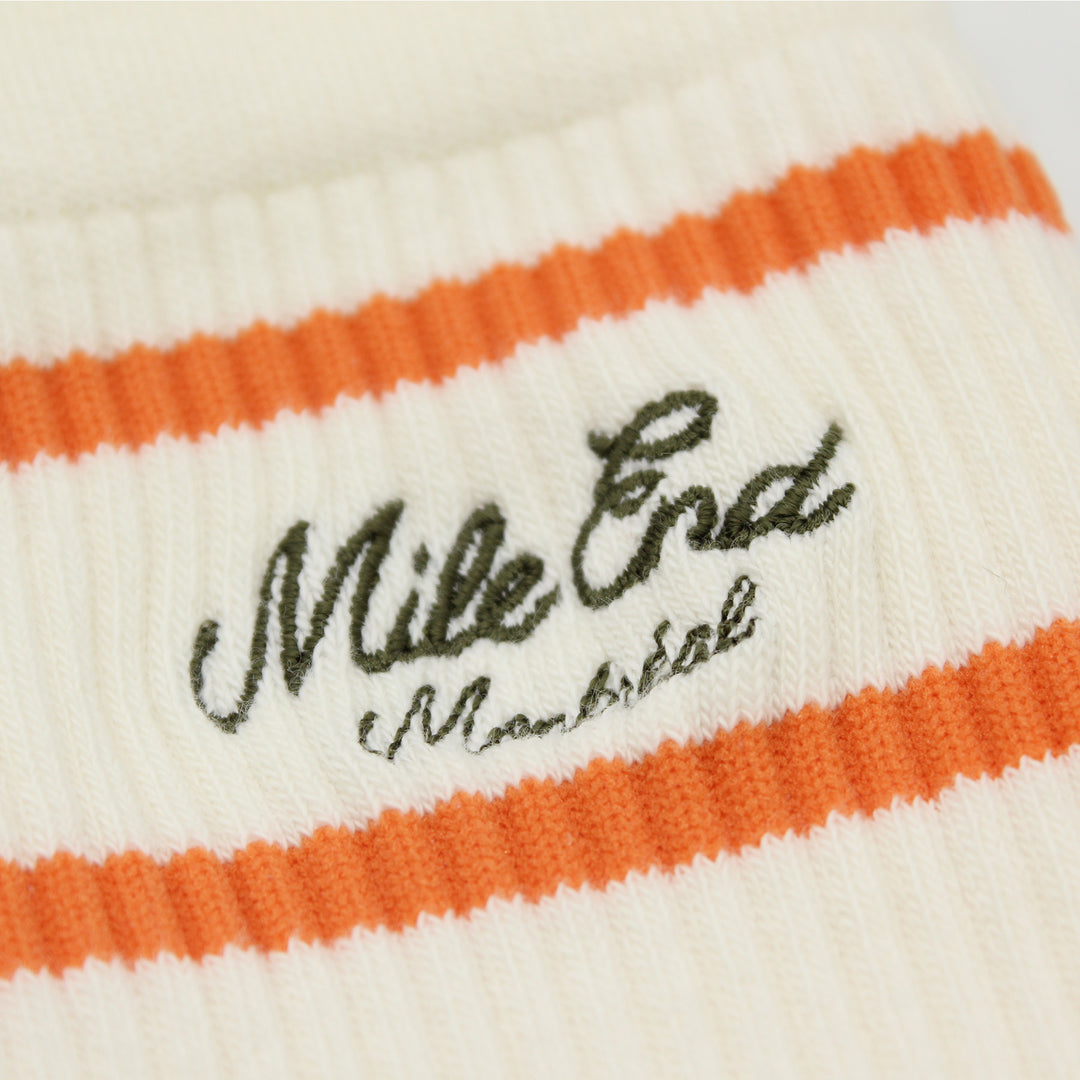Close-up of a white and orange striped fabric with 'Mile End' branding.