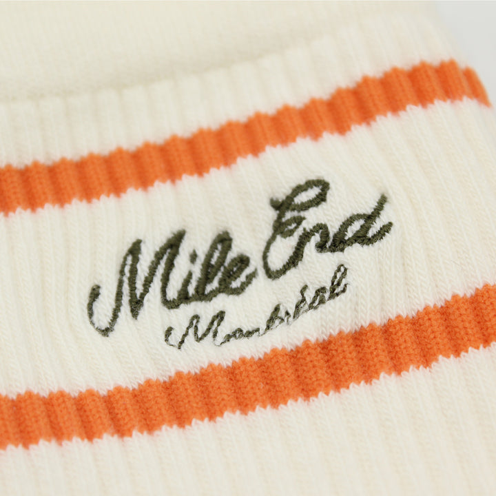 Close-up of a white and orange striped fabric with 'Mile End' branding.