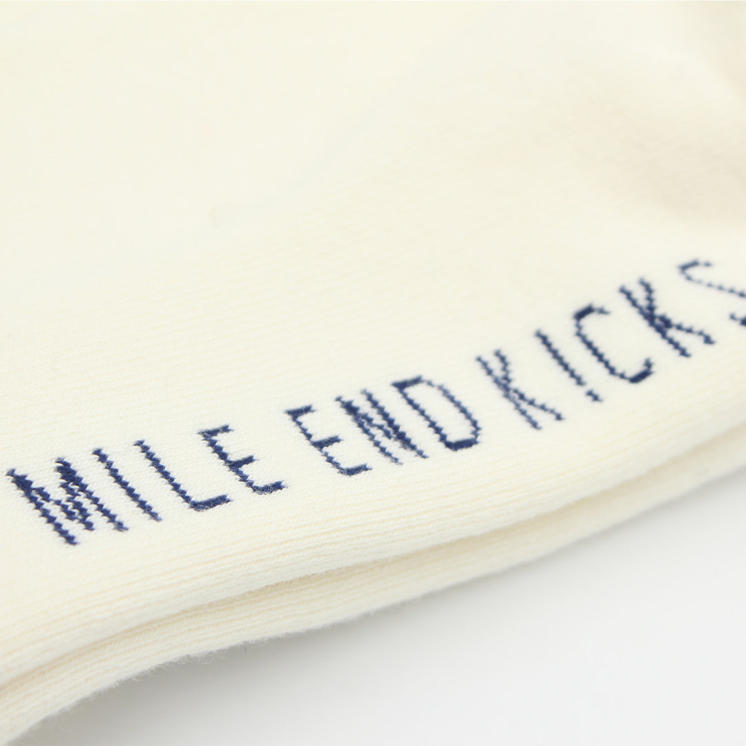 Close-up of a white sock with blue text 'MILE END KICKS' on a light background
