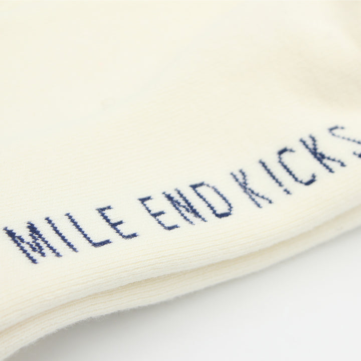 Close-up of a white sock with blue text 'MILE END KICKS' on a light background